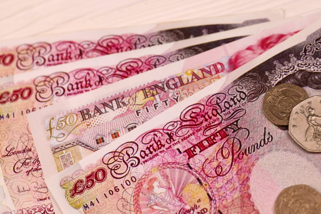Close-up of £50 and £20 British banknotes with coins, highlighting financial security and money management services.