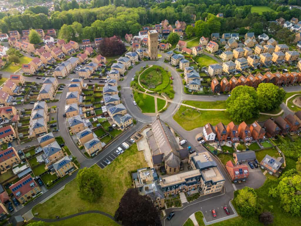 Aerial view of a residential neighbourhood with a church, surrounded by greenery and houses, illustrating property investigation and historical research.