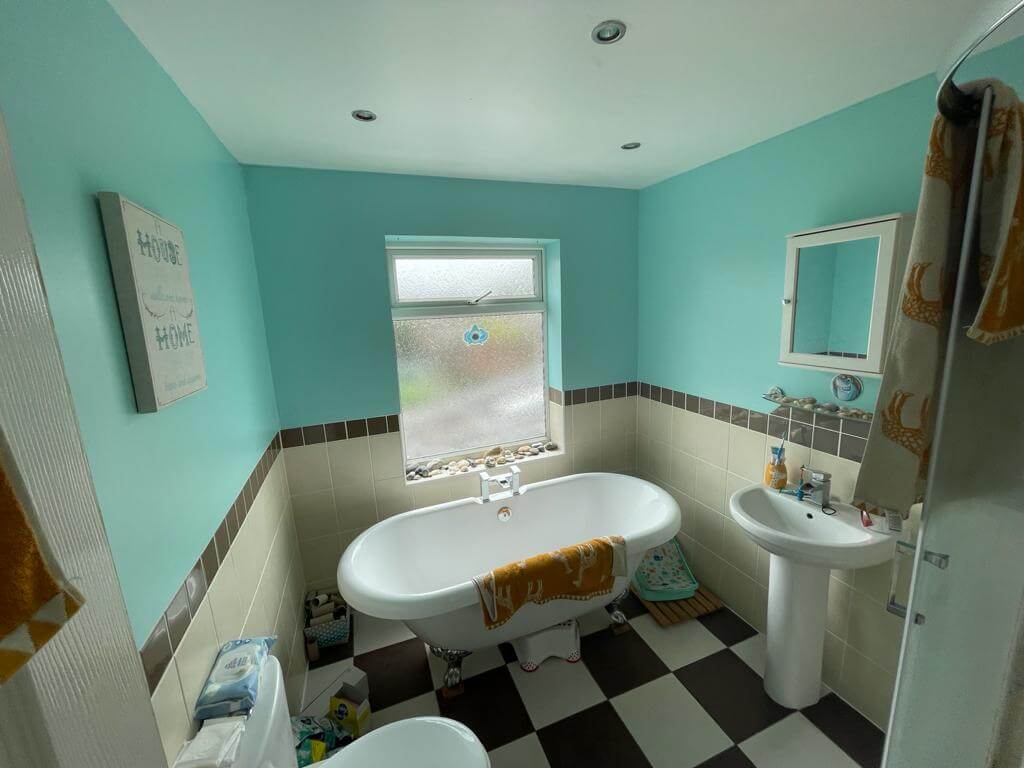 Bright bathroom with turquoise walls, freestanding bathtub, and modern fixtures, ideal for relaxation and property luxury, showcased by Property Saviour.