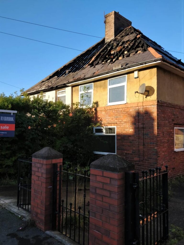 Damaged roof of a house with missing tiles, highlighting the need for roof repair and property maintenance services.