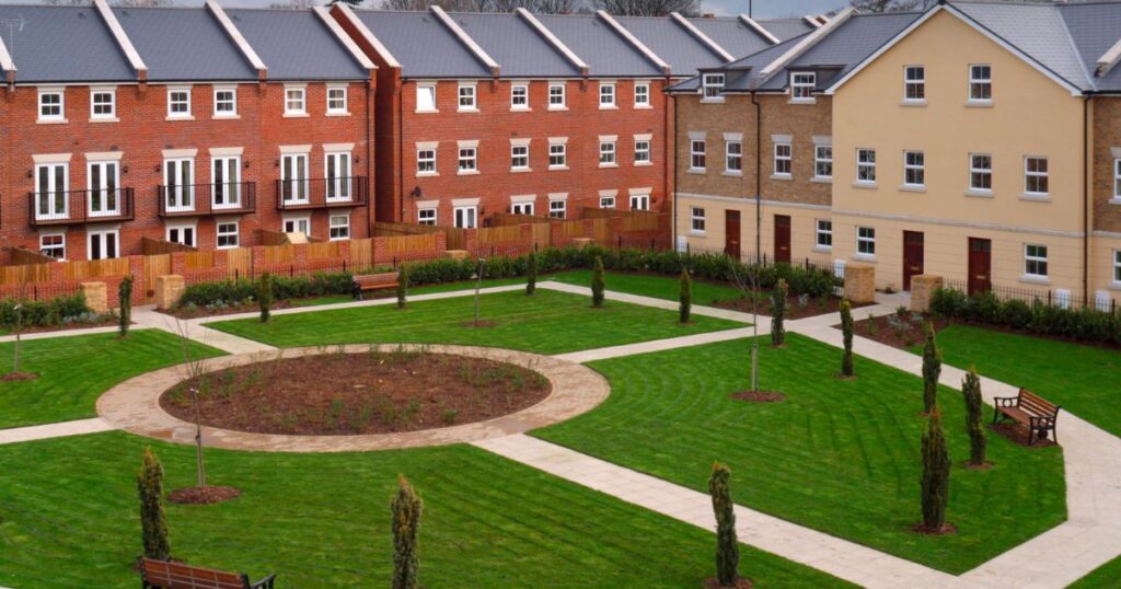 Well-maintained residential courtyard with green lawns, trees, and benches, illustrating communal outdoor space for homeowners.