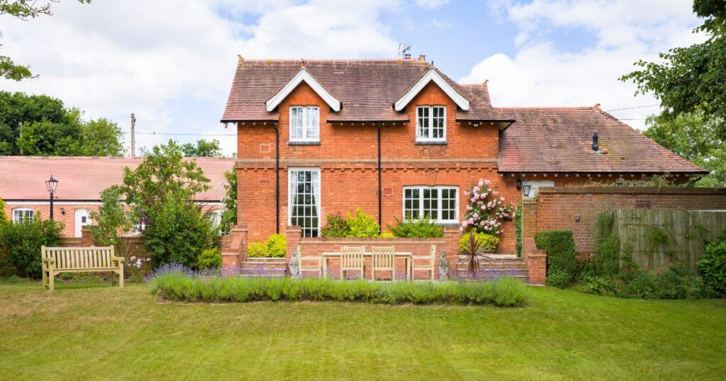 Traditional red brick house with a well-maintained garden, representing property ownership and legal documentation related to house deeds.