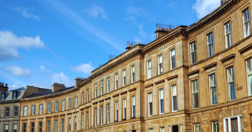 Historic urban building with classic architecture under a bright blue sky, showcasing traditional stonework and large windows. Perfect for property investment and renovation projects.