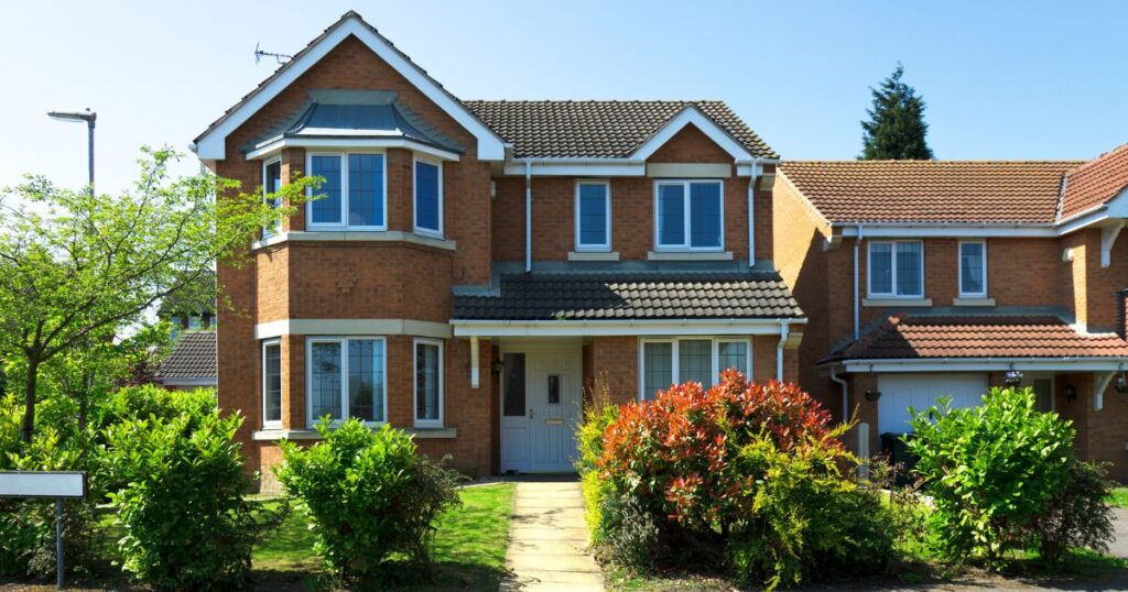 Modern detached house with well-maintained garden and clear blue sky, showcasing property renovation and protection services.
