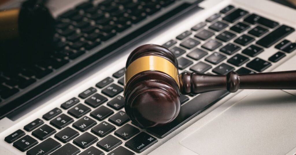 Wooden gavel resting on a laptop keyboard, symbolising online legal proceedings and digital justice.