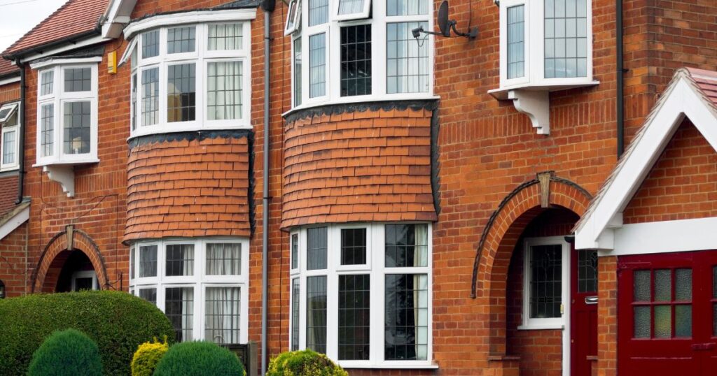 Attractive red brick residential building with bay windows and white trim, showcasing traditional architecture and well-maintained exterior.