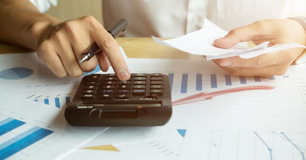 Calculator for property financial calculations, paper receipts and financial documents on a wooden desk.