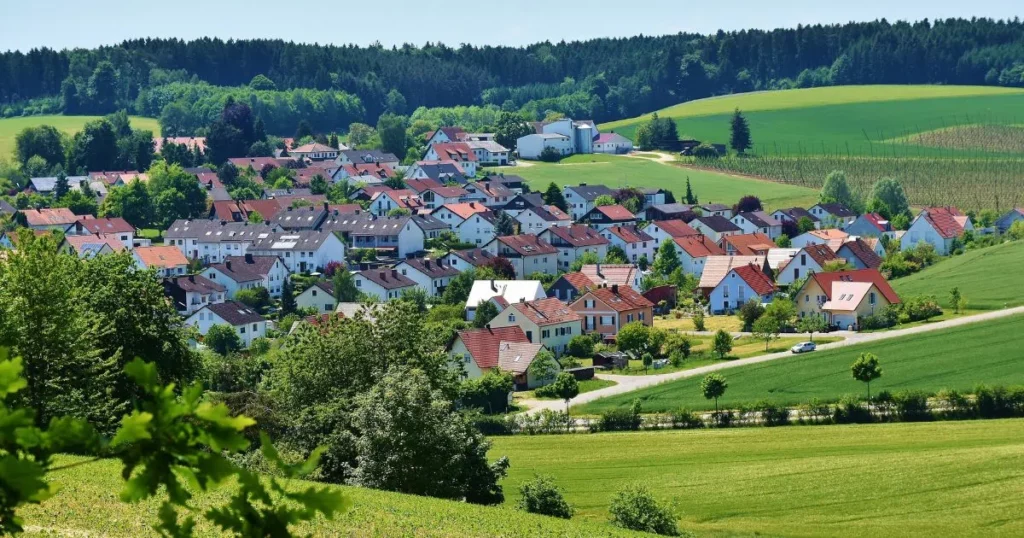 Vibrant village surrounded by lush green fields and rolling hills, showcasing scenic countryside with colourful houses and rural landscapes.