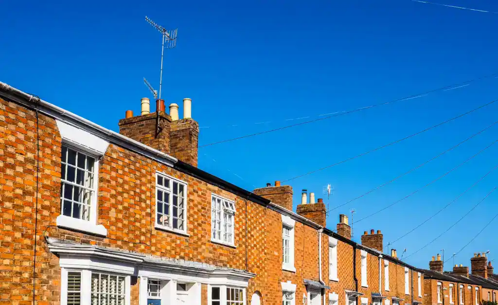 Row of traditional brick terraced houses under a clear blue sky, illustrating the difficulties of selling a property after a parent's passing.