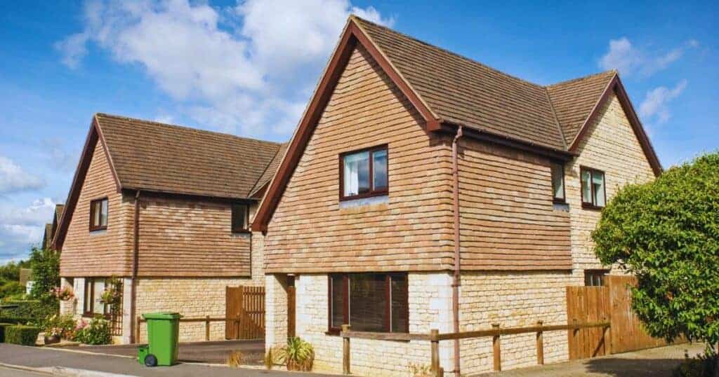 Stunning modern residential property with brick and wooden exterior, well-maintained garden, and clear blue sky, showcasing effective property preservation and property management solutions.