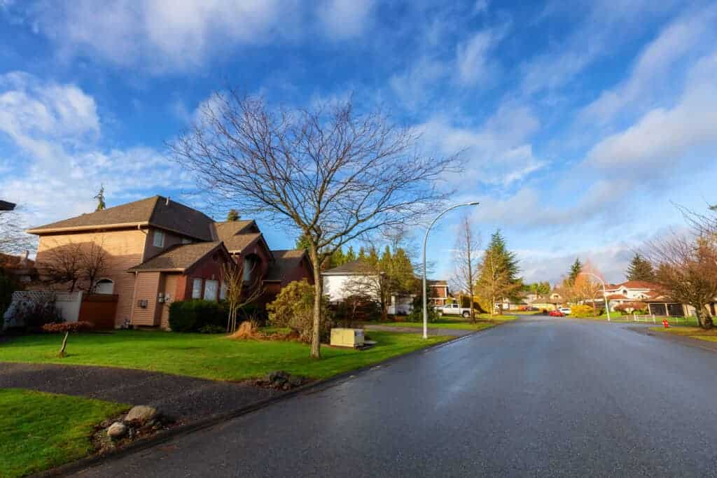 Lush suburban street in the UK with beautiful homes, green lawns, and clear skies, exemplifying property protection and real estate services by Property Saviour.