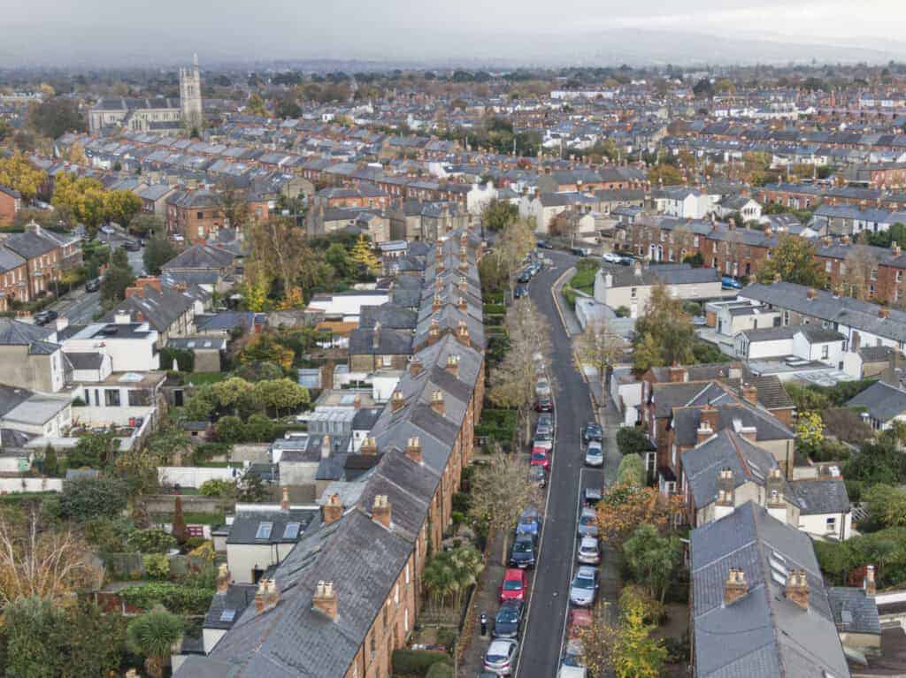 Aerial view of a charming residential neighbourhood showcasing terraced houses, tree-lined streets, and lush gardens, ideal for homeowners seeking property valuation and market insights from Property Saviour.