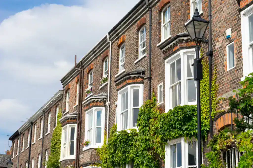 Victorian terraced houses with bay windows and greenery, illustrating property transfer processes in the UK.