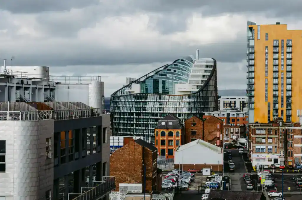 Modern commercial building in an urban cityscape with surrounding structures under a cloudy sky.