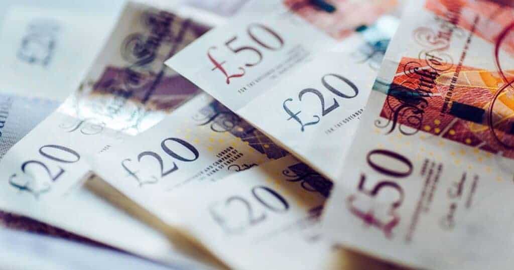 Dirty £20 and £50 banknotes scattered on a surface.