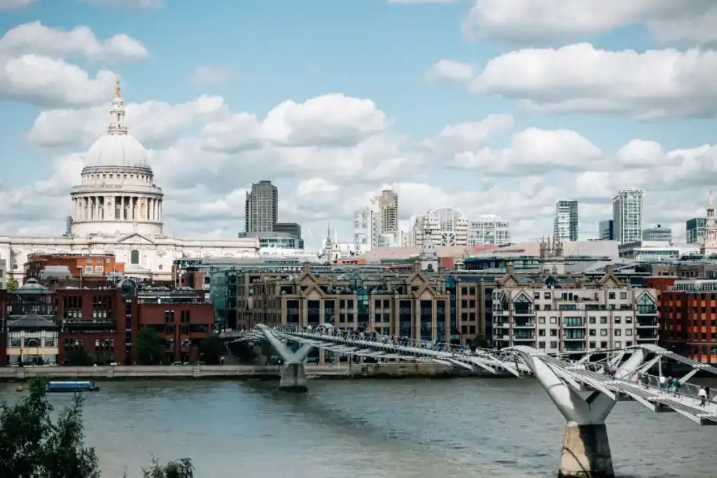 London cityscape with historic and modern buildings, including St. Paul's Cathedral, under a partly cloudy sky.