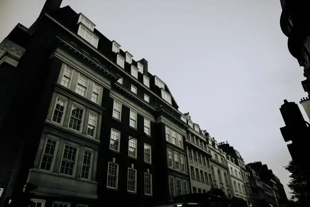 Modern multi-storey building with classic architectural details, located in an urban setting, under a cloudy sky.