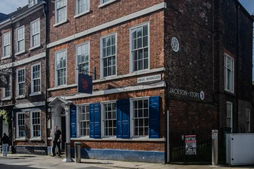 Historic brick building with blue window shutters, located in a busy city street, offering commercial property leasing opportunities. Perfect for investors seeking leaseback options.