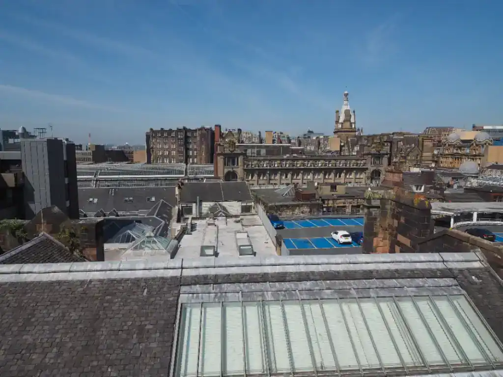 A panoramic view of city rooftops showcasing historic and modern buildings under a clear blue sky, highlighting urban commercial property features.