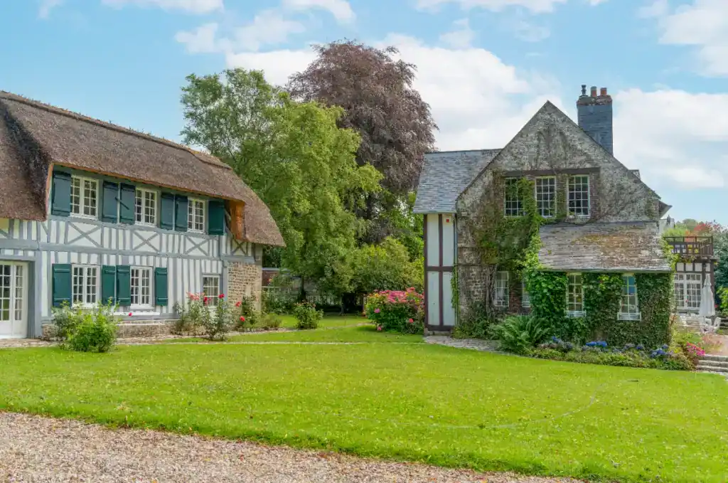 A picturesque view of traditional English cottages with lush greenery and well-maintained gardens, illustrating the importance of proof of funds in property transactions.