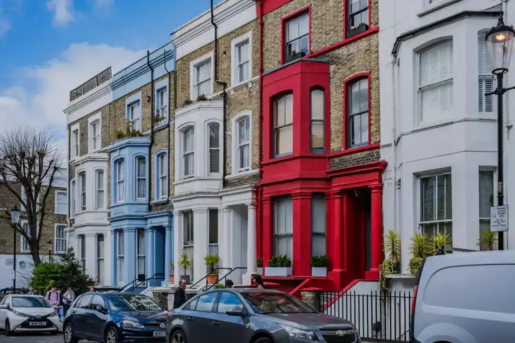 Colourful Victorian townhouses in London with bay windows and front gardens, showcasing classic architecture and vibrant facades.