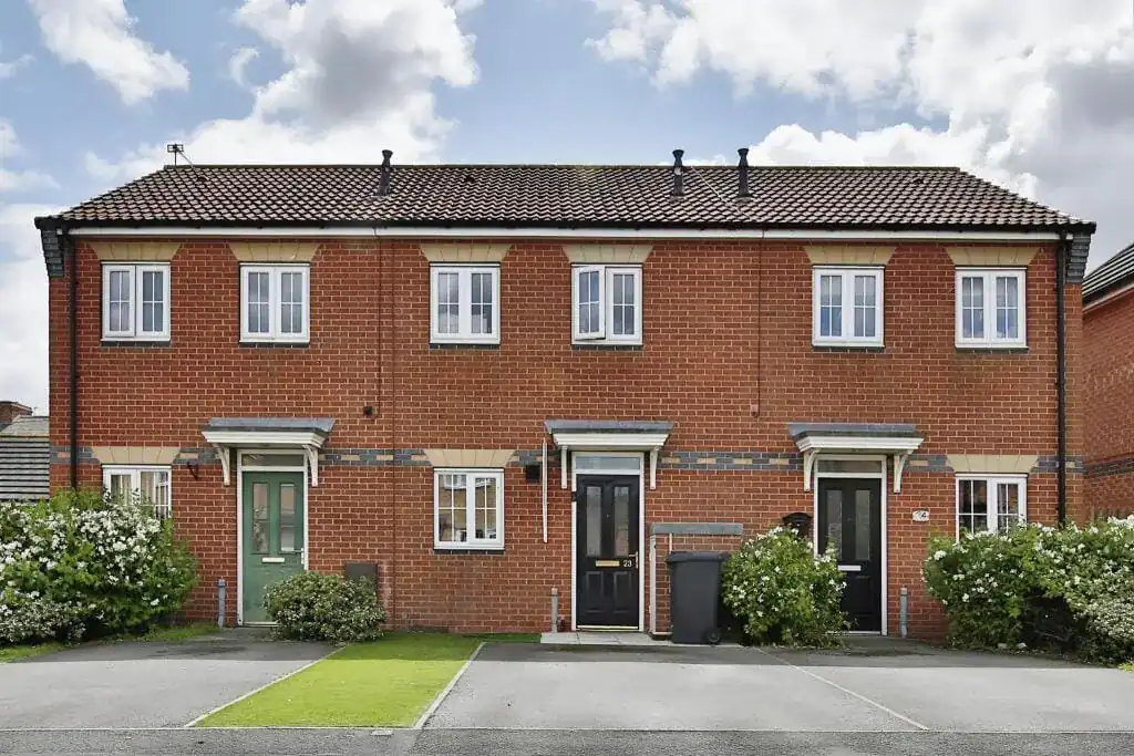 Modern brick townhouses in England with well-maintained front gardens, ideal for budget-friendly homebuyers seeking affordable housing options.