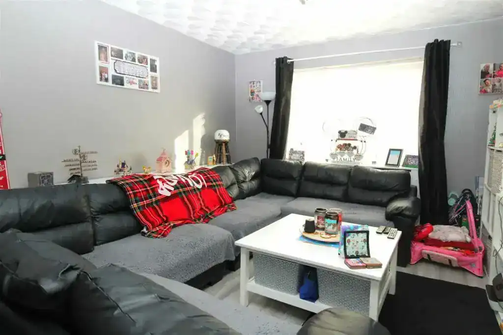 Modern living room with black sectional sofa, white coffee table, and personal decor, showcasing a cosy family space in a home in England.