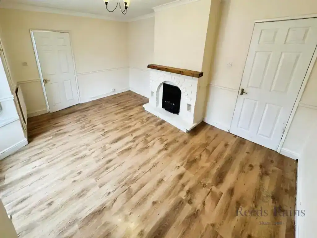 Bright and airy living room featuring a wooden floor, white walls, and a fireplace, ideal for comfortable living in affordable UK homes.
