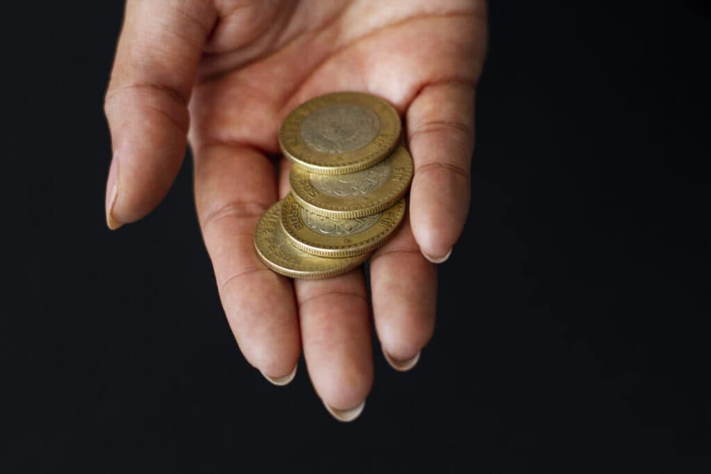Hand holding a small stack of coins, symbolising financial transactions related to property and family inheritance.