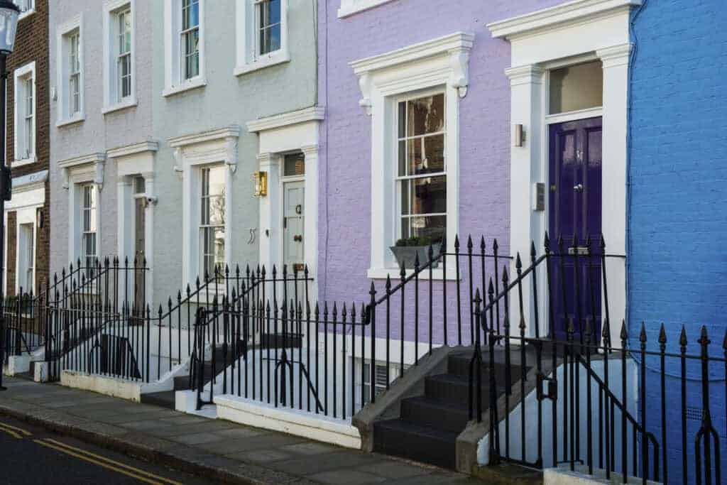 Brightly painted row houses with steps leading to front doors, showcasing vibrant colours and charming architecture.