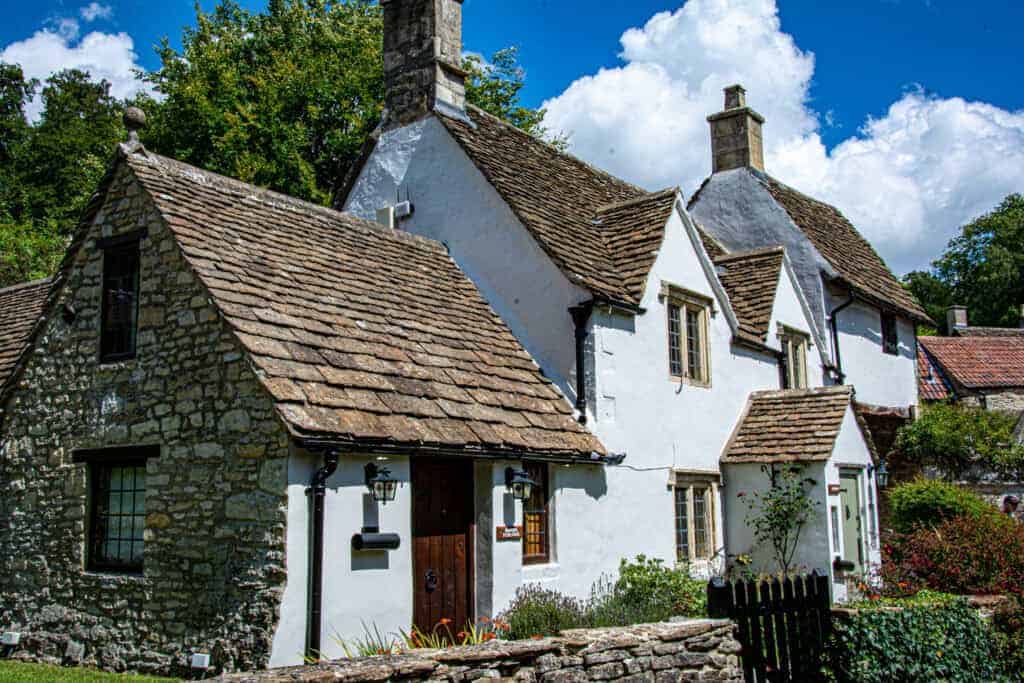 Rustic cottage with traditional stone and whitewashed walls, charming pitched roofs, and lush greenery, perfect for property restoration and renovation services in historic homes.