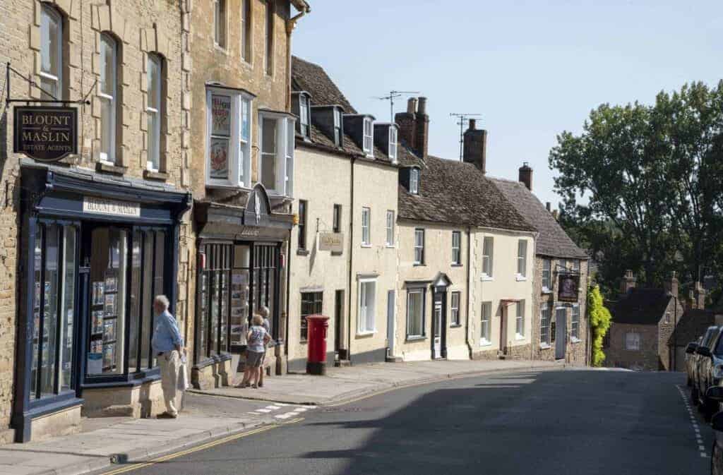 Traditional UK high street with estate agent storefront, showcasing local properties and a busy street scene, relevant to property offers and estate agency services.