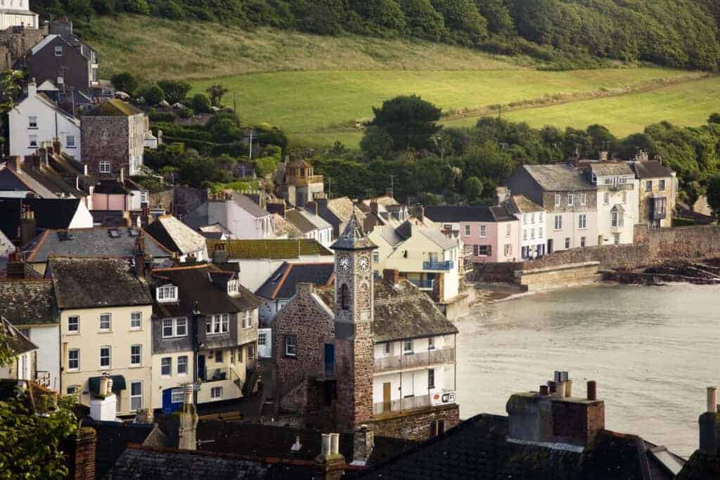 1. Charming coastal village with colourful houses, historic clock tower, and scenic harbour views, perfect for property investment or holiday homes in seaside settings.