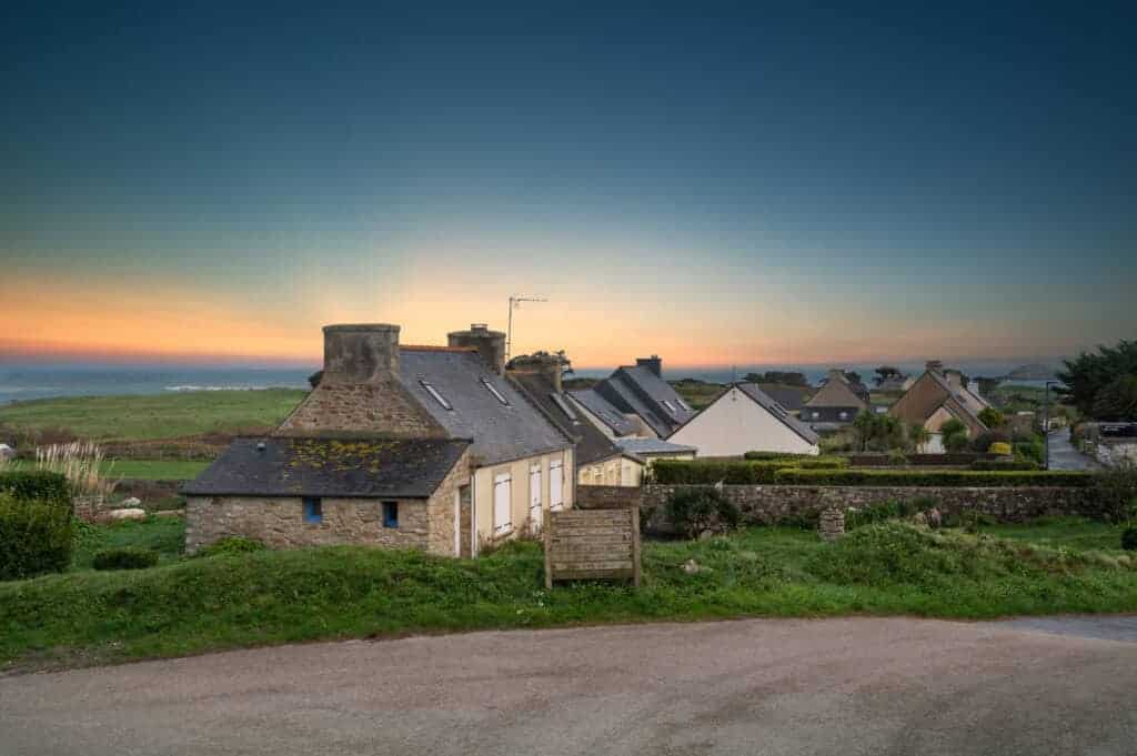 Peaceful coastal village with traditional stone cottages at sunset, showcasing property preservation and scenic views for real estate investment or holiday home opportunities.