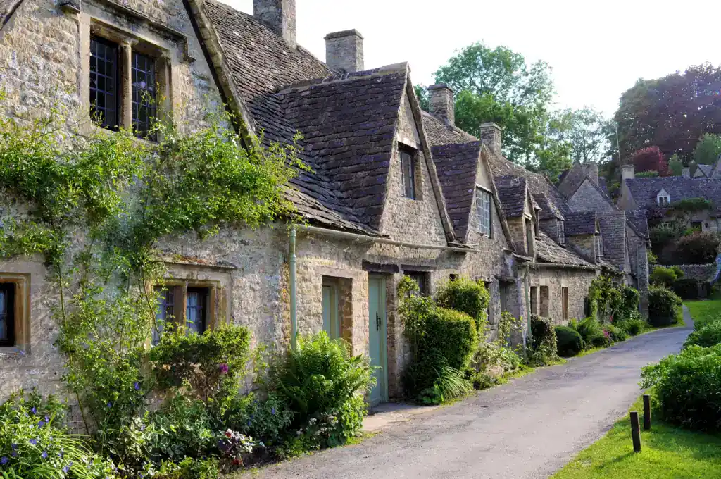 Charming historic stone cottages with lush garden greenery in a picturesque village setting, promoting property restoration and estate management services.