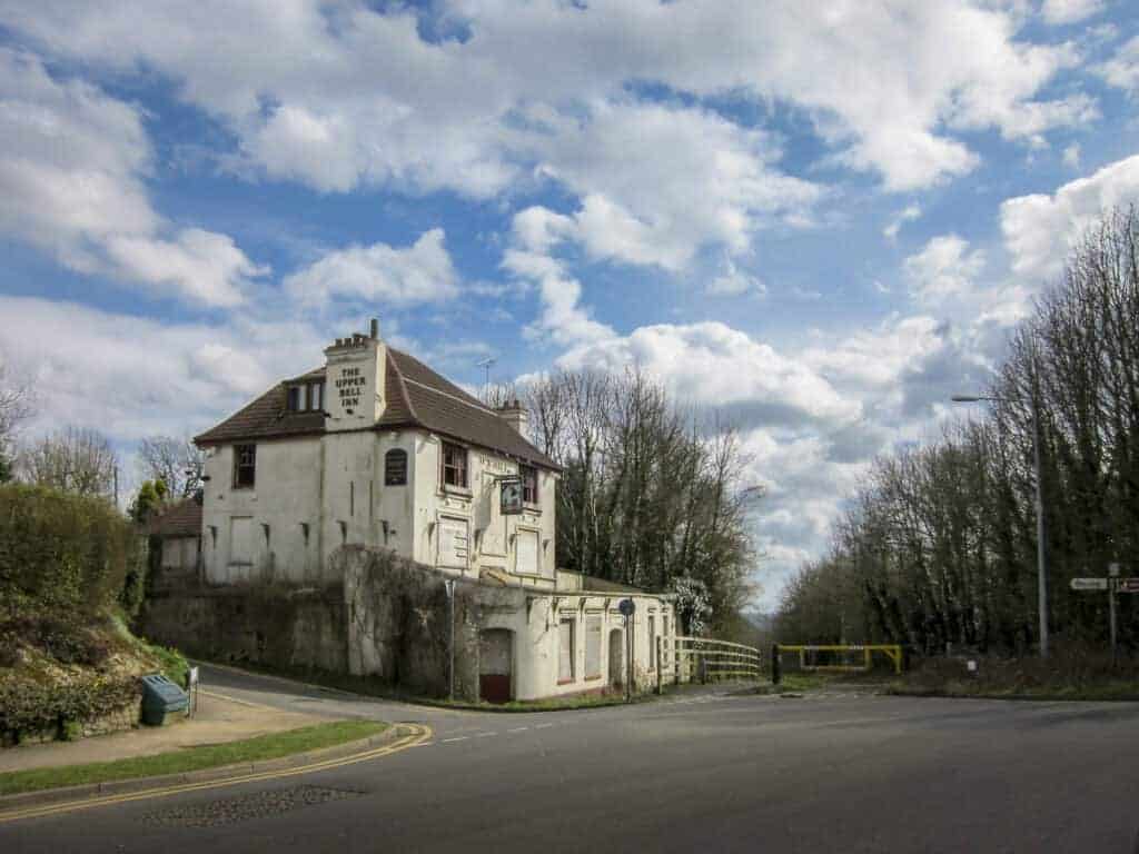 1. A historic, old building with a sign reading "The Upper Bell Inn" situated at a street corner under a partly cloudy sky.