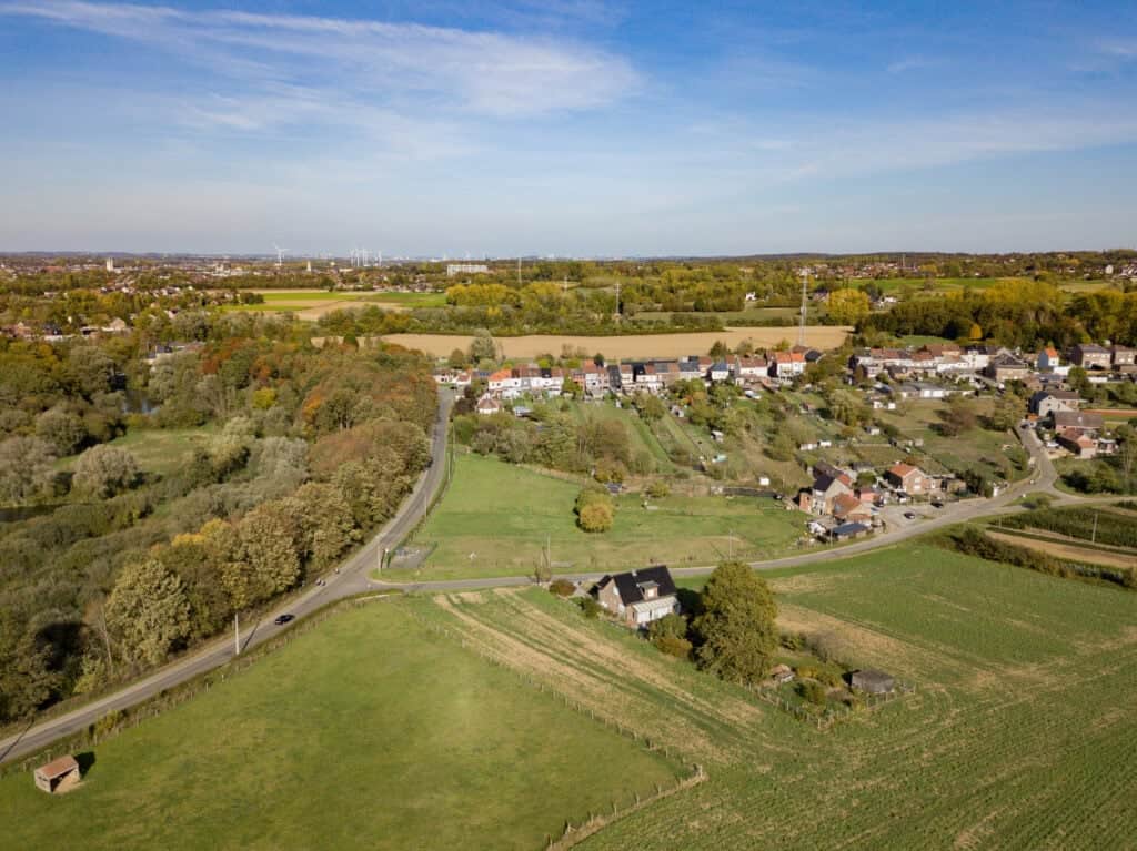 Versatile aerial view of scenic countryside with lush greenery, winding roads, and a small village, highlighting property locations and beautiful landscape in a peaceful rural setting.