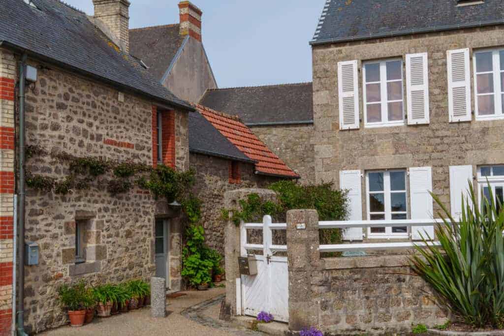Charming historic stone cottages with traditional architecture and white shutters, nestled in a picturesque village setting, showcasing quality property renovation services.