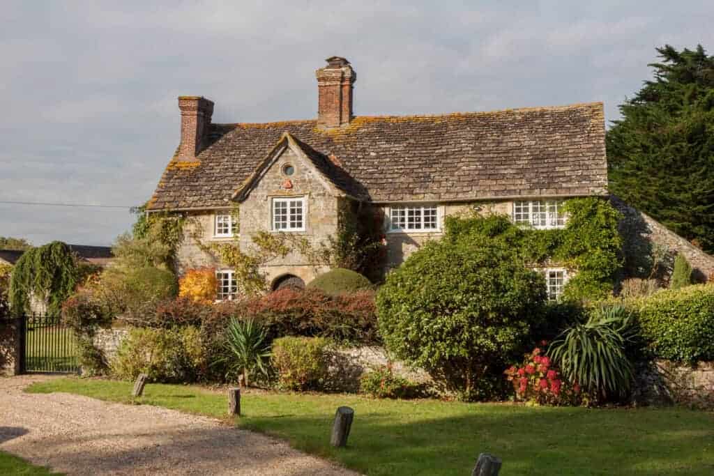 Beautiful traditional cottage surrounded by lush garden greenery and vibrant flowers, ideal for retirees considering selling or renting their home.