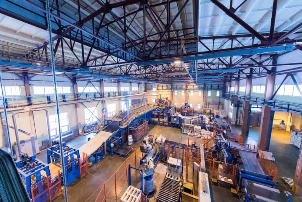 Industrial warehouse interior showcasing machinery, storage racks, and high ceilings, highlighting the scale and functionality of commercial property spaces.