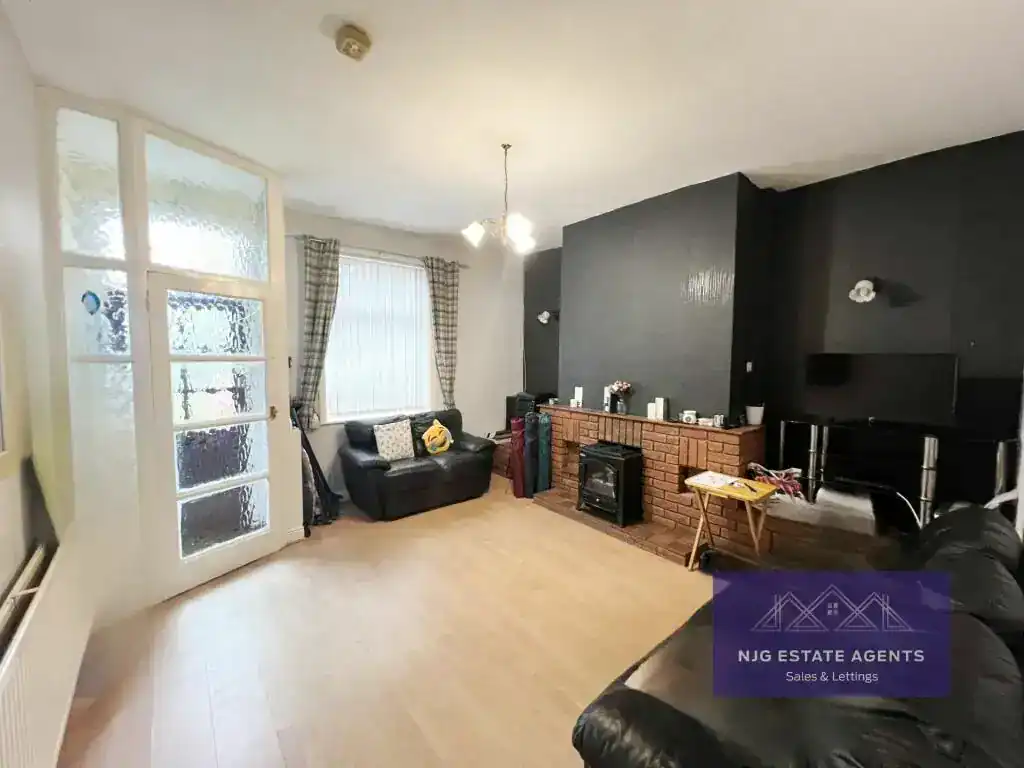 Bright living room featuring a fireplace, large window with curtains, and comfortable seating, ideal for relaxing in a budget-friendly home in England.
