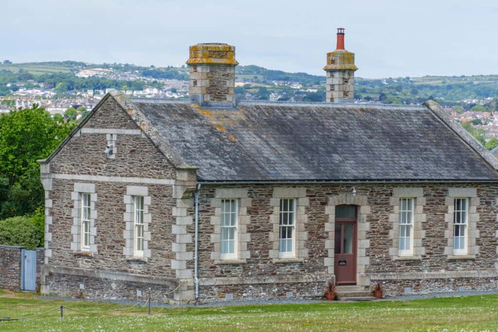 Weathered stone cottage with two chimneys, overlooking a scenic landscape, showcasing historic property features.