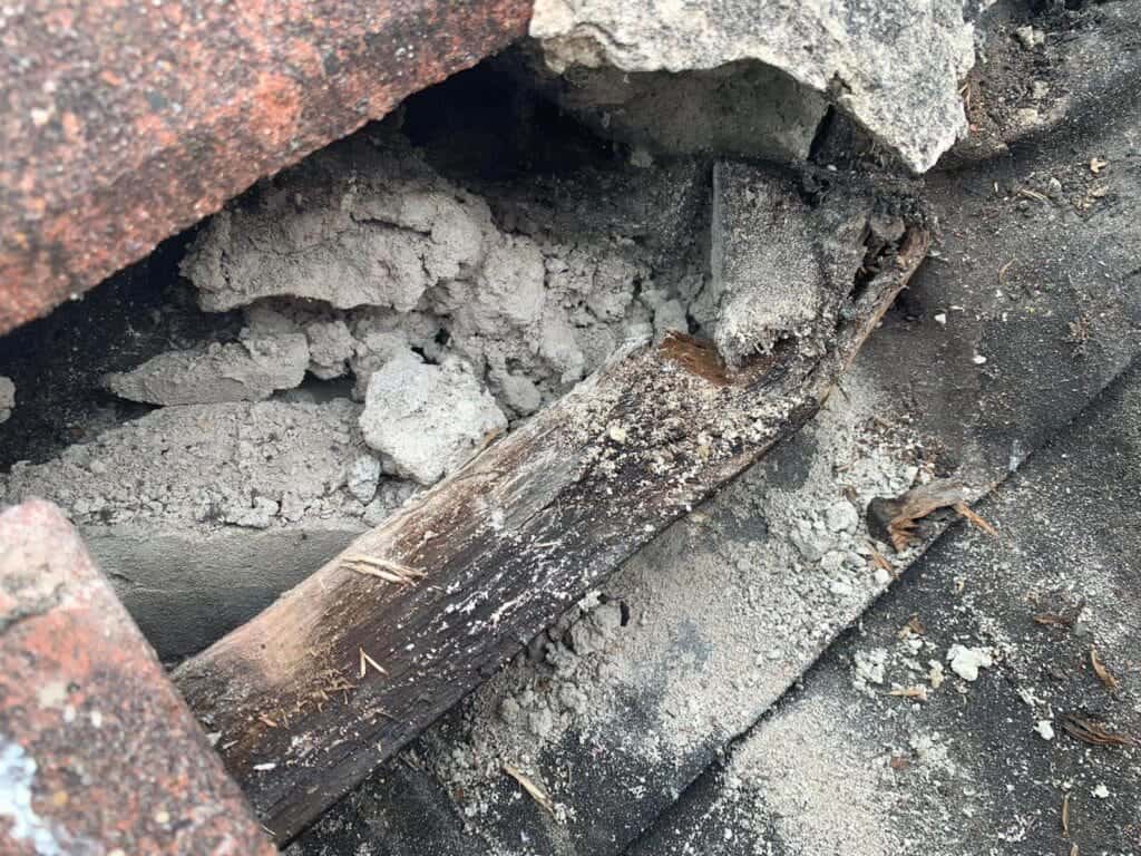 An image showing damaged roofing with a leaking roof, including broken tiles and exposed wood, highlighting the importance of professional roof repairs to prevent further property damage.