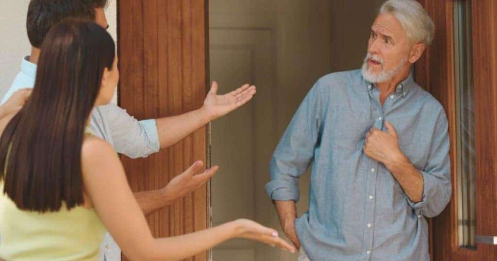 Elderly man having a heated discussion with neighbours at his front door about neighbour issues.