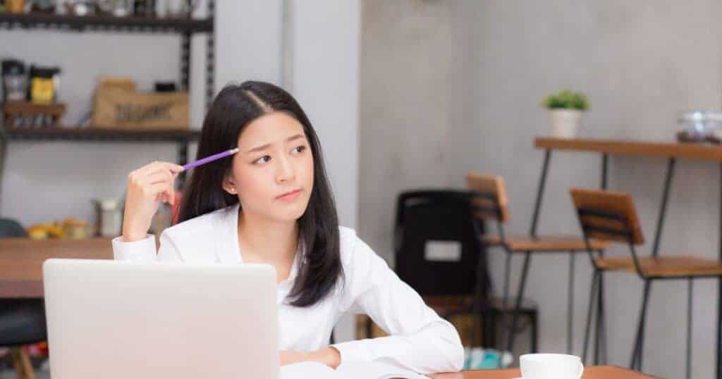 A woman working at a desk, contemplating property issues, with a focus on legal and boundary considerations related to selling a house without a party wall agreement.