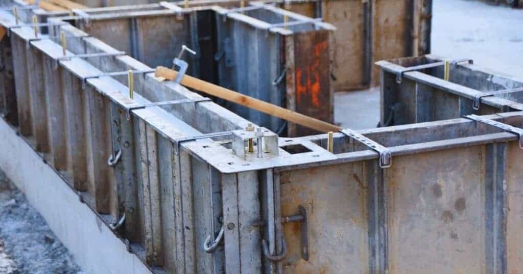 Concrete foundation formwork with steel reinforcement for house construction, illustrating foundation preparation.