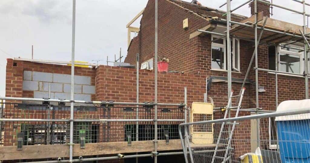 Construction site showing brickwork and scaffolding for a property renovation, highlighting building control considerations for house sales.