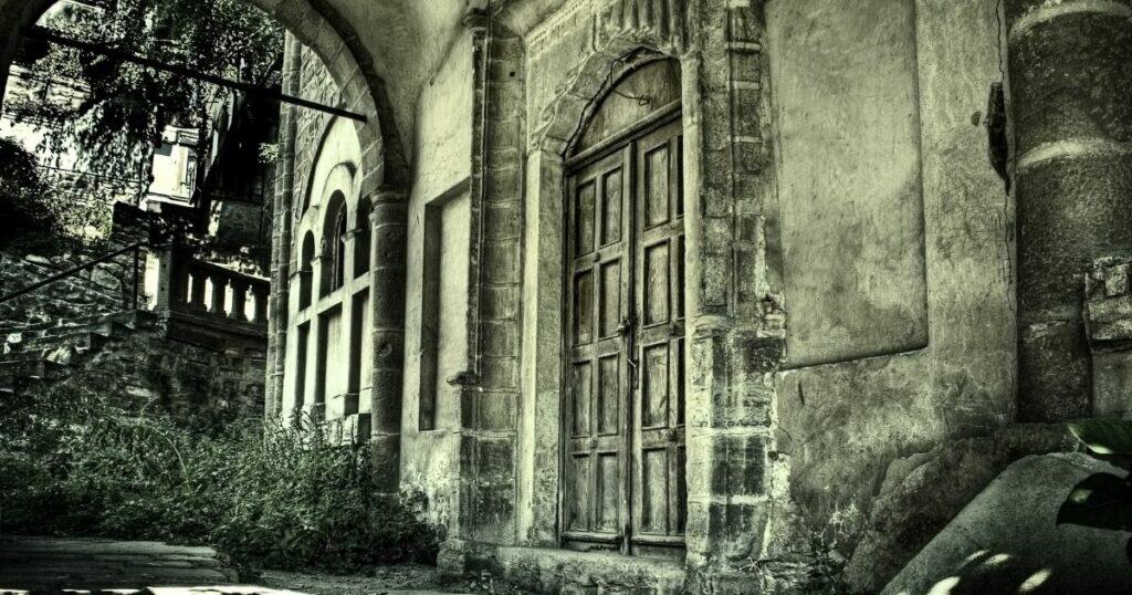 Old haunted house with weathered stone facade and wooden door, set in a mysterious, eerie environment perfect for ghost stories.